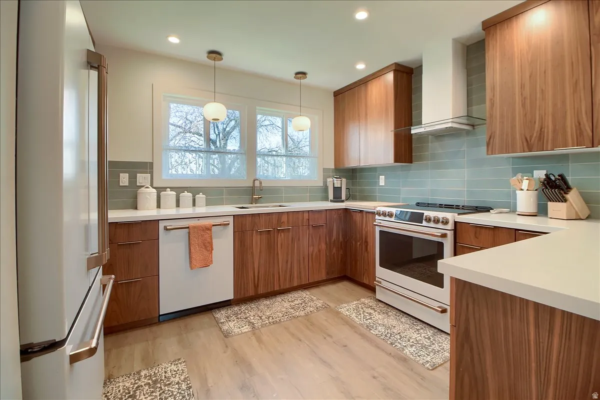 Kitchen featuring wood-finish cabinetry, high-end appliances, and light wood-type flooring.