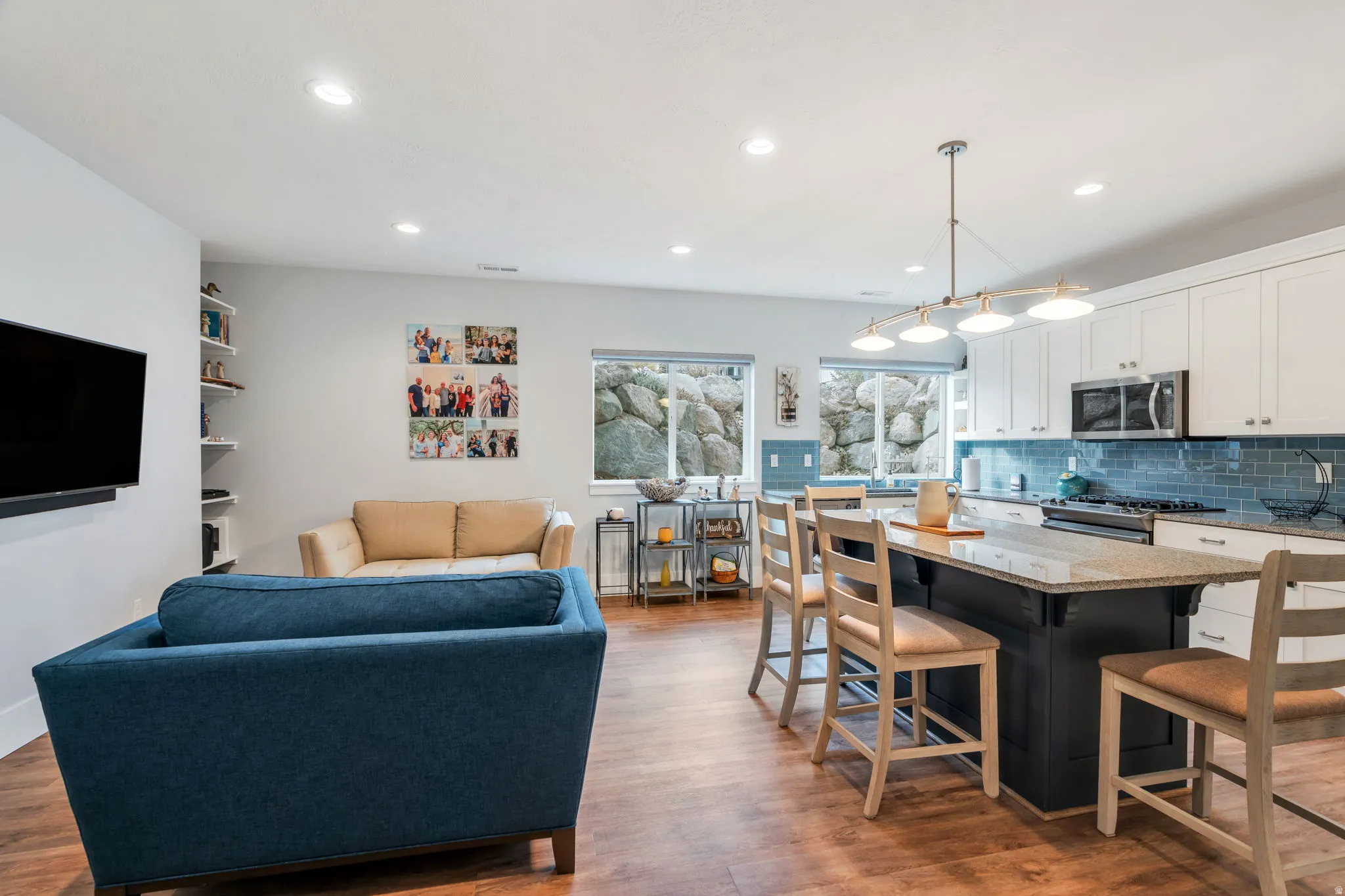 Two tone kitchen featuring light stone countertops, a kitchen bar, a center island, stainless steel appliances, and light wood-style floors
