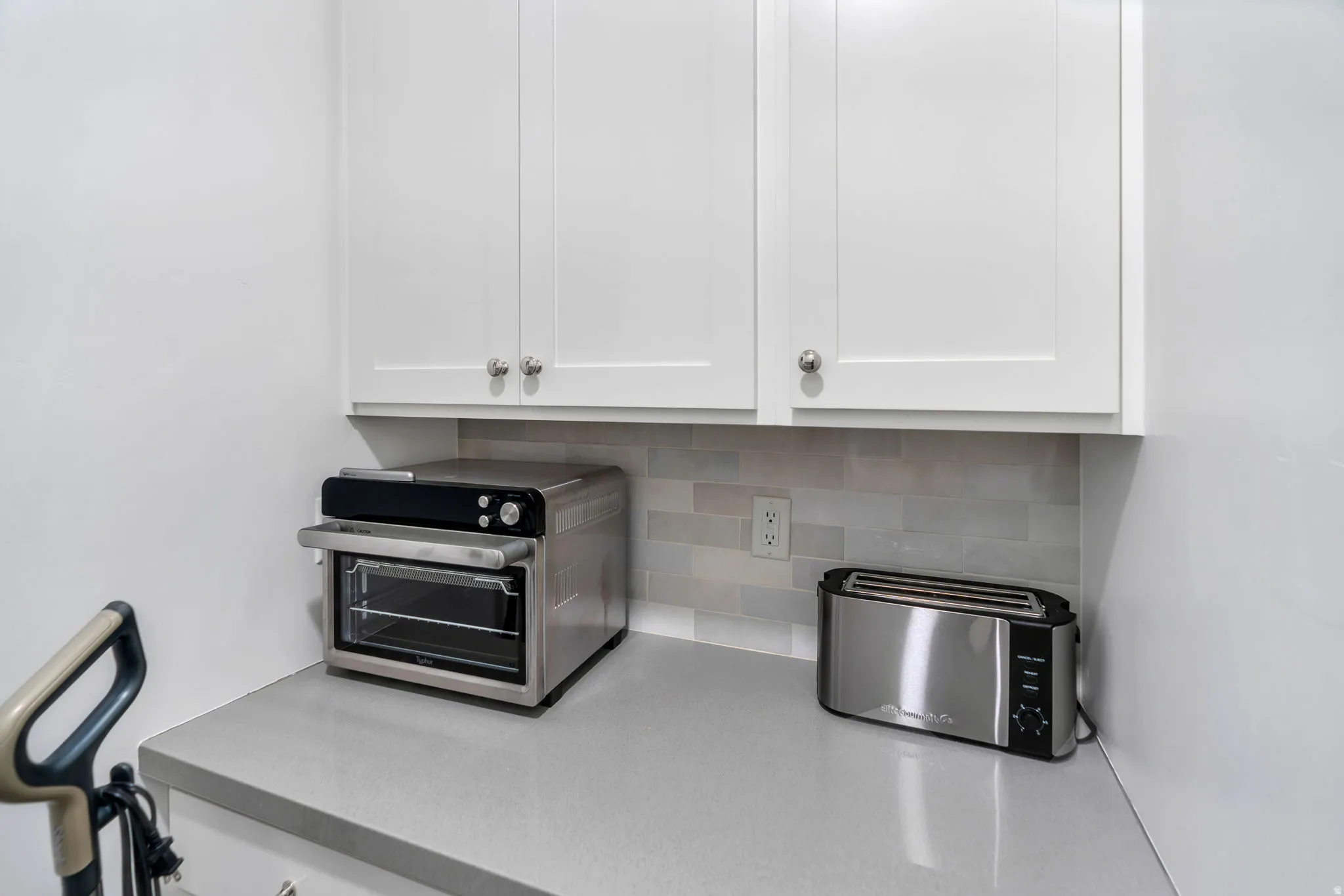 Kitchen view of white cabinets and tasteful backsplash