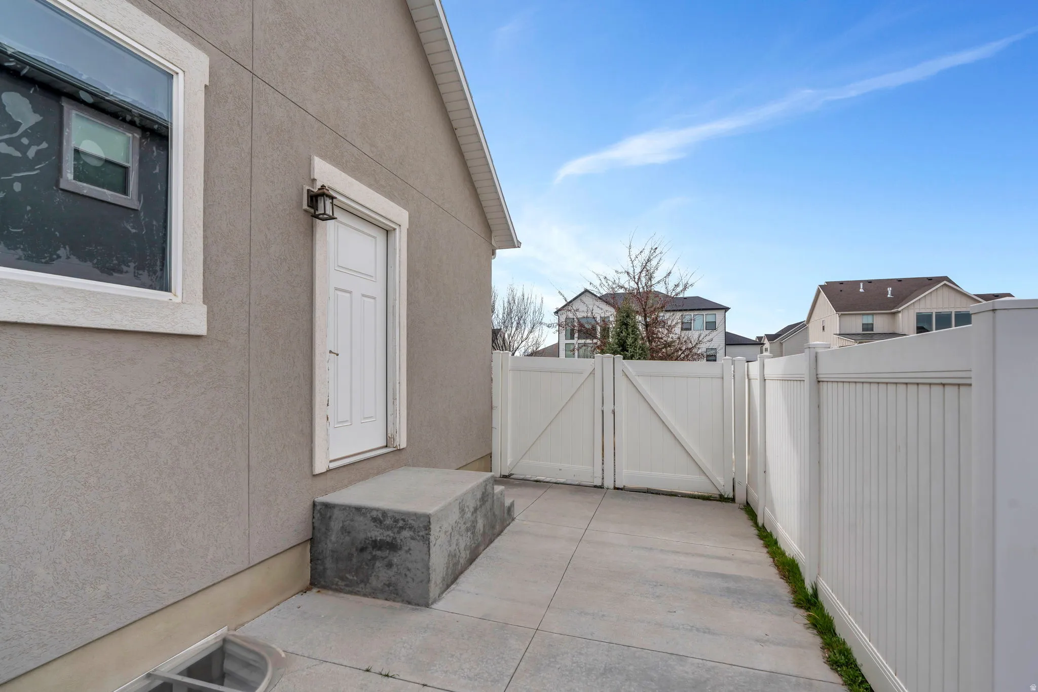 Property entrance with a gate, stucco siding, and a patio area