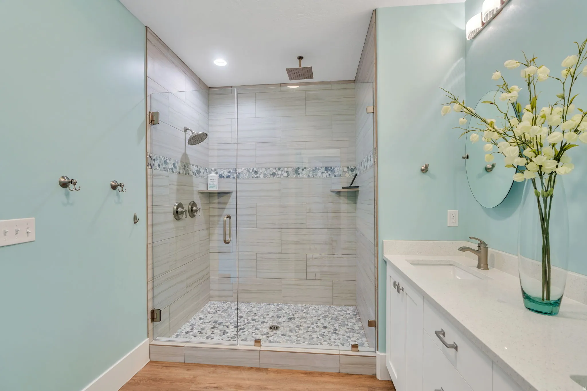 Bathroom with double vanity, a stall shower, light wood finished floors, and recessed lighting