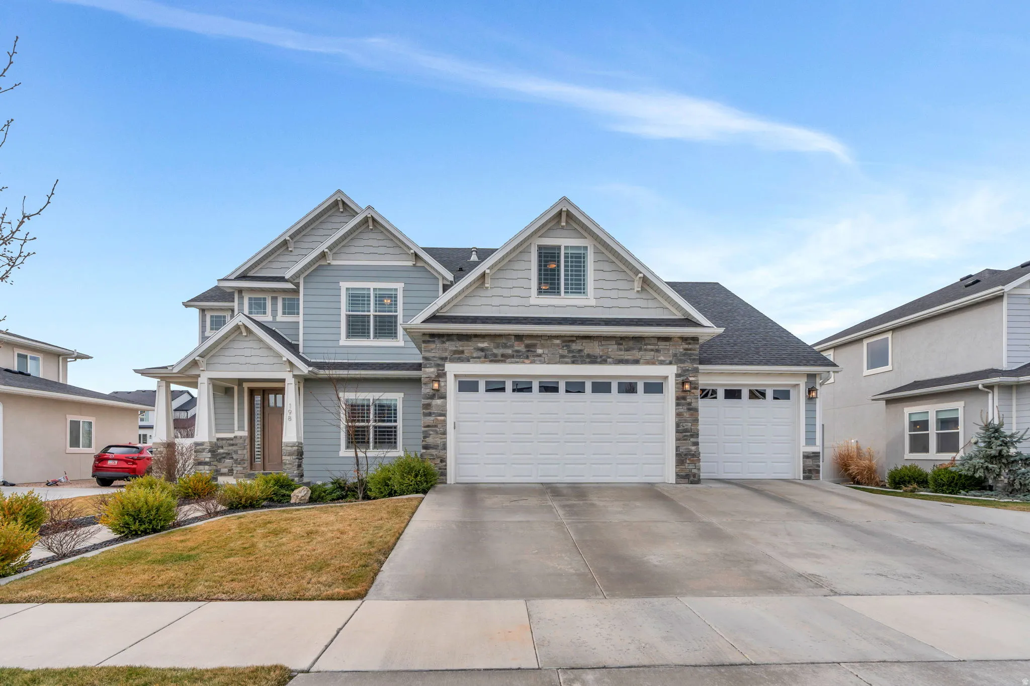 Craftsman-style home featuring stone siding, concrete driveway, a front lawn, and a garage