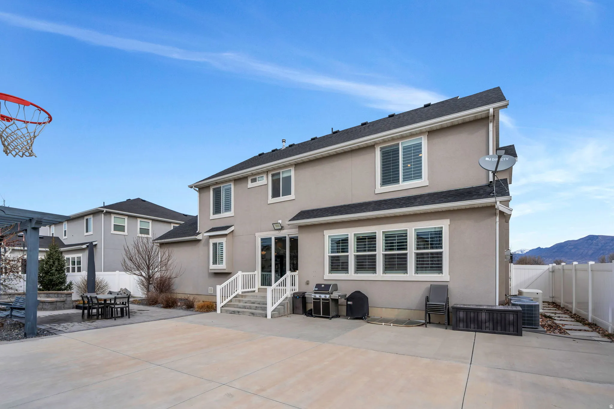 Rear view of house featuring a patio, outdoor dining space, stucco siding, a mountain view, and roof with shingles