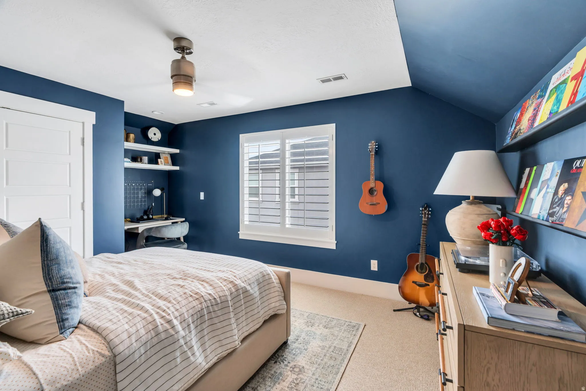 Bedroom with light carpet, an office area, and vaulted ceiling