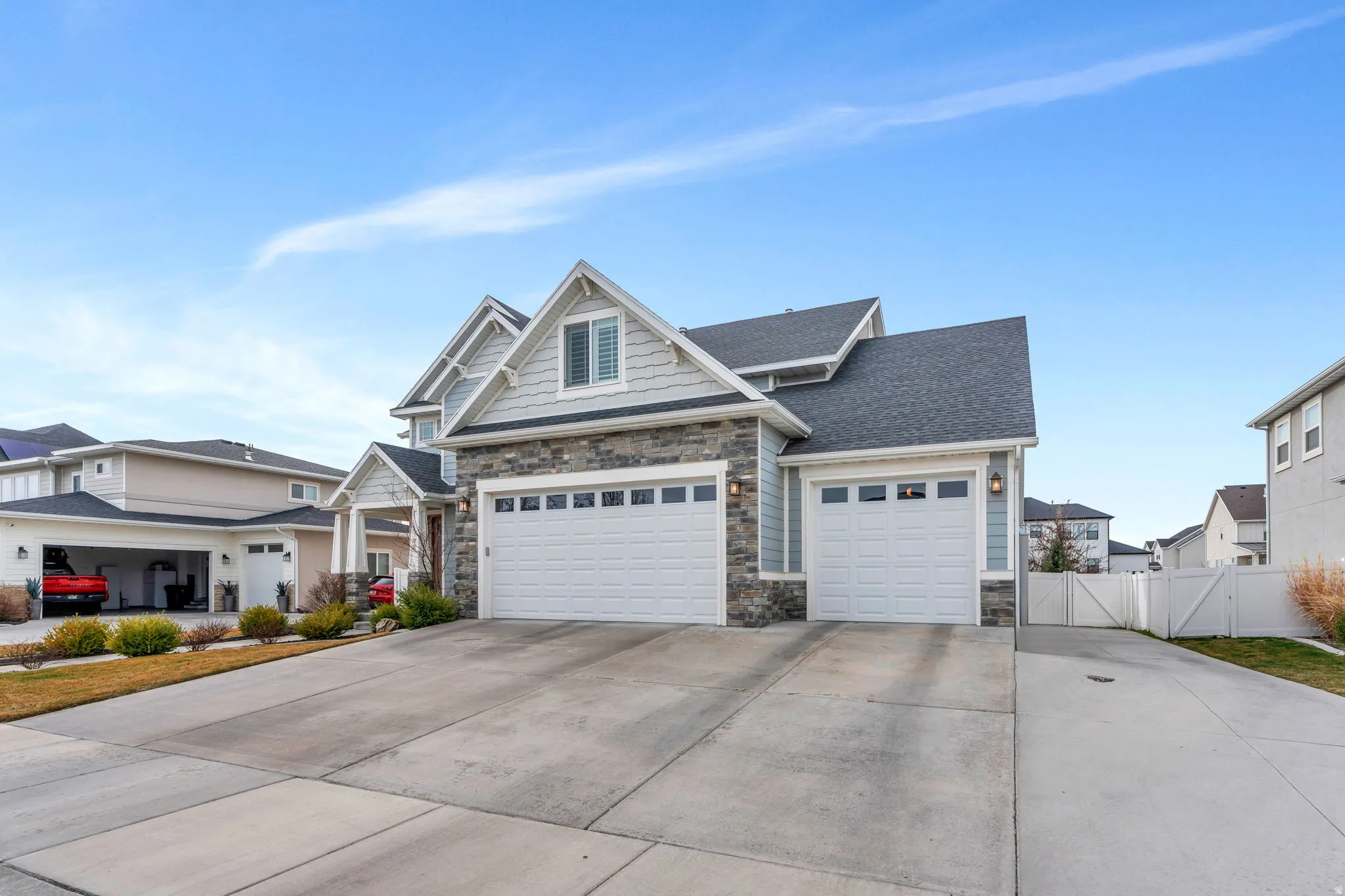 Craftsman house featuring a gate, stone siding, concrete driveway, a garage, and roof with shingles