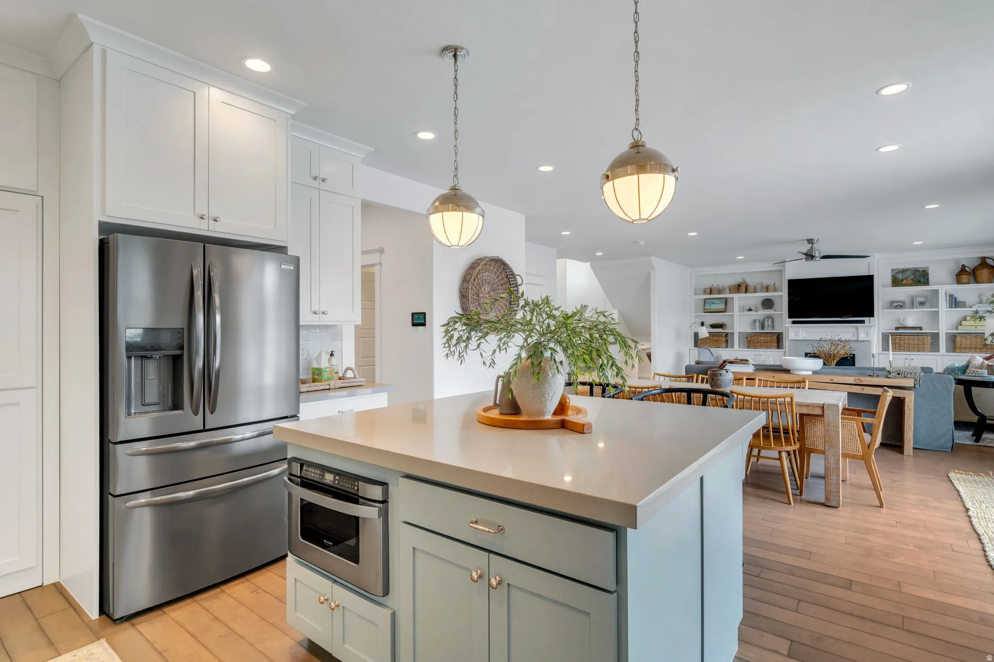 Two tone kitchen featuring stainless steel appliances, a kitchen island, open floor plan, hanging light fixtures, and two tone color scheme