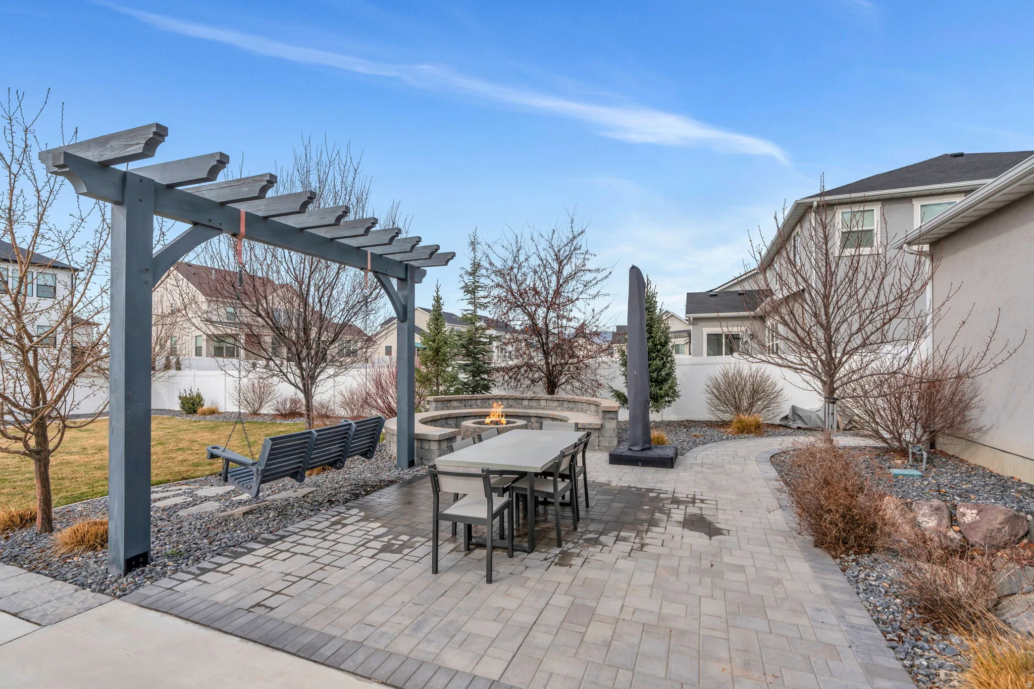Fenced backyard with a patio area, an outdoor fire pit, a pergola, and outdoor dining space