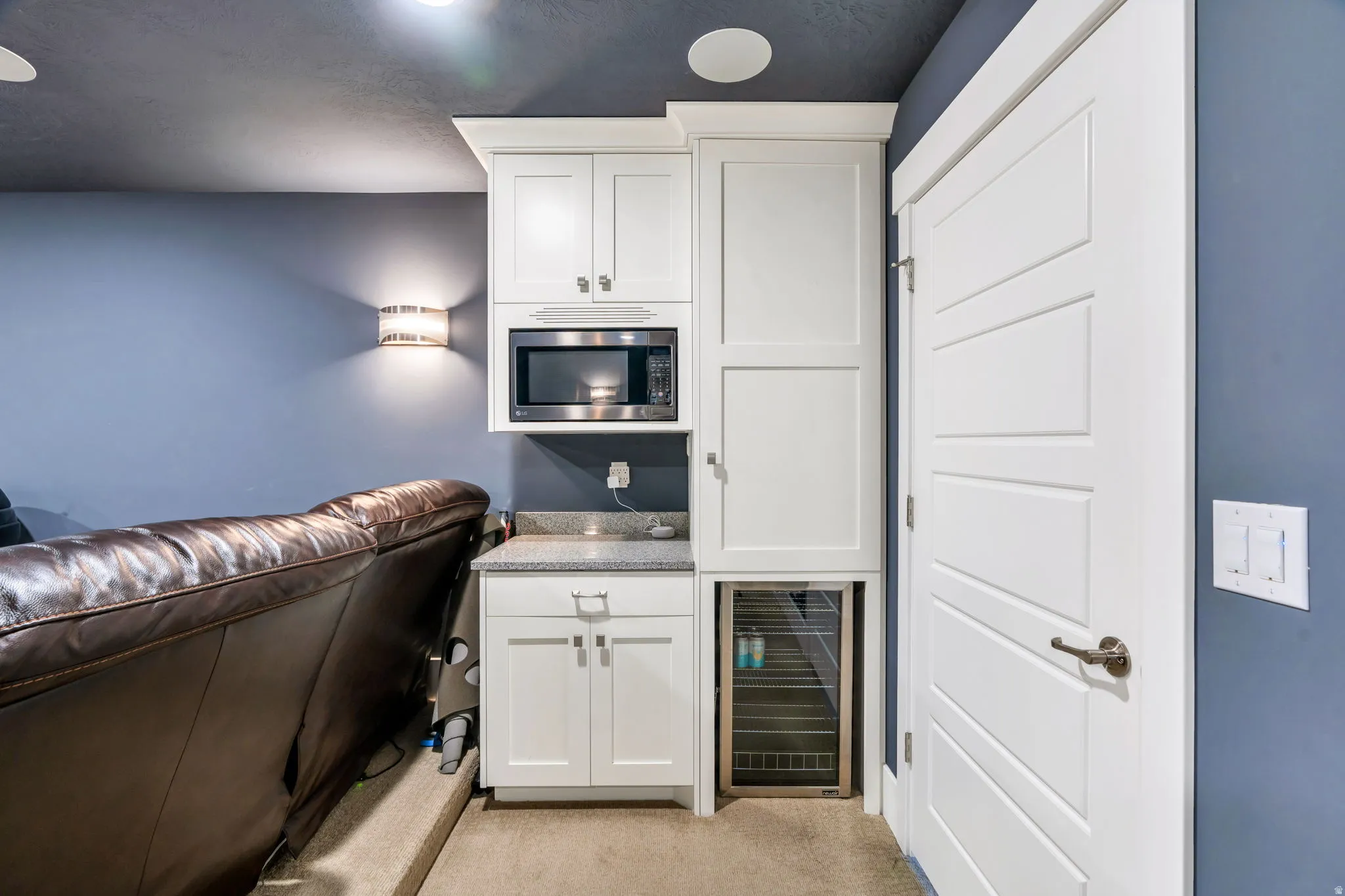 Bar featuring wine cooler, white cabinets, stainless steel microwave, and light colored carpet