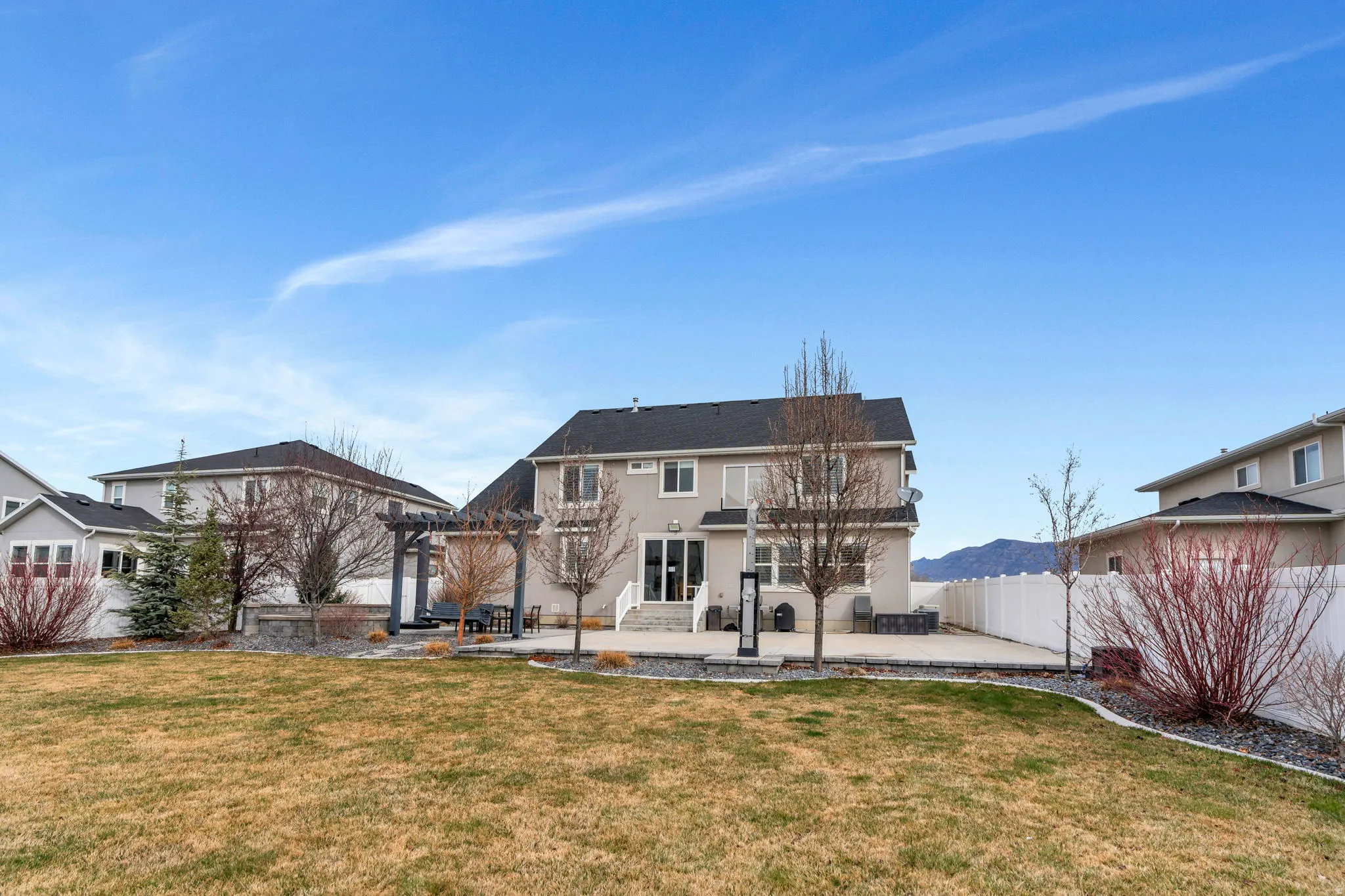 Back of property featuring a patio, a fenced backyard, a pergola, and stucco siding