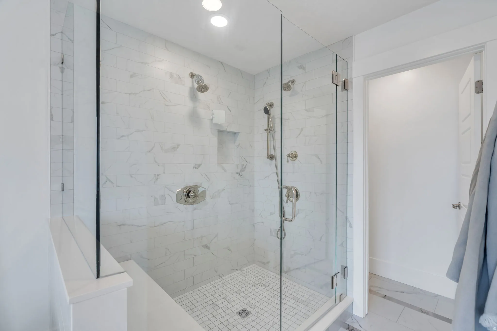 Bathroom with a marble finish shower and recessed lighting