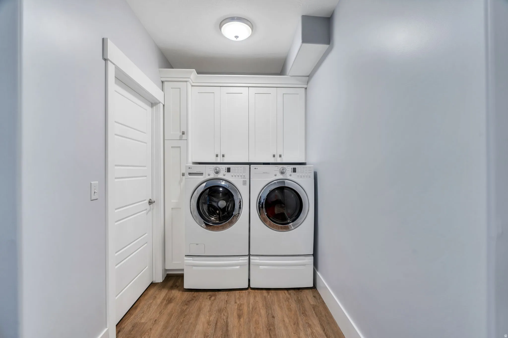 Laundry area with cabinet space, light wood-type flooring, and washing machine and dryer