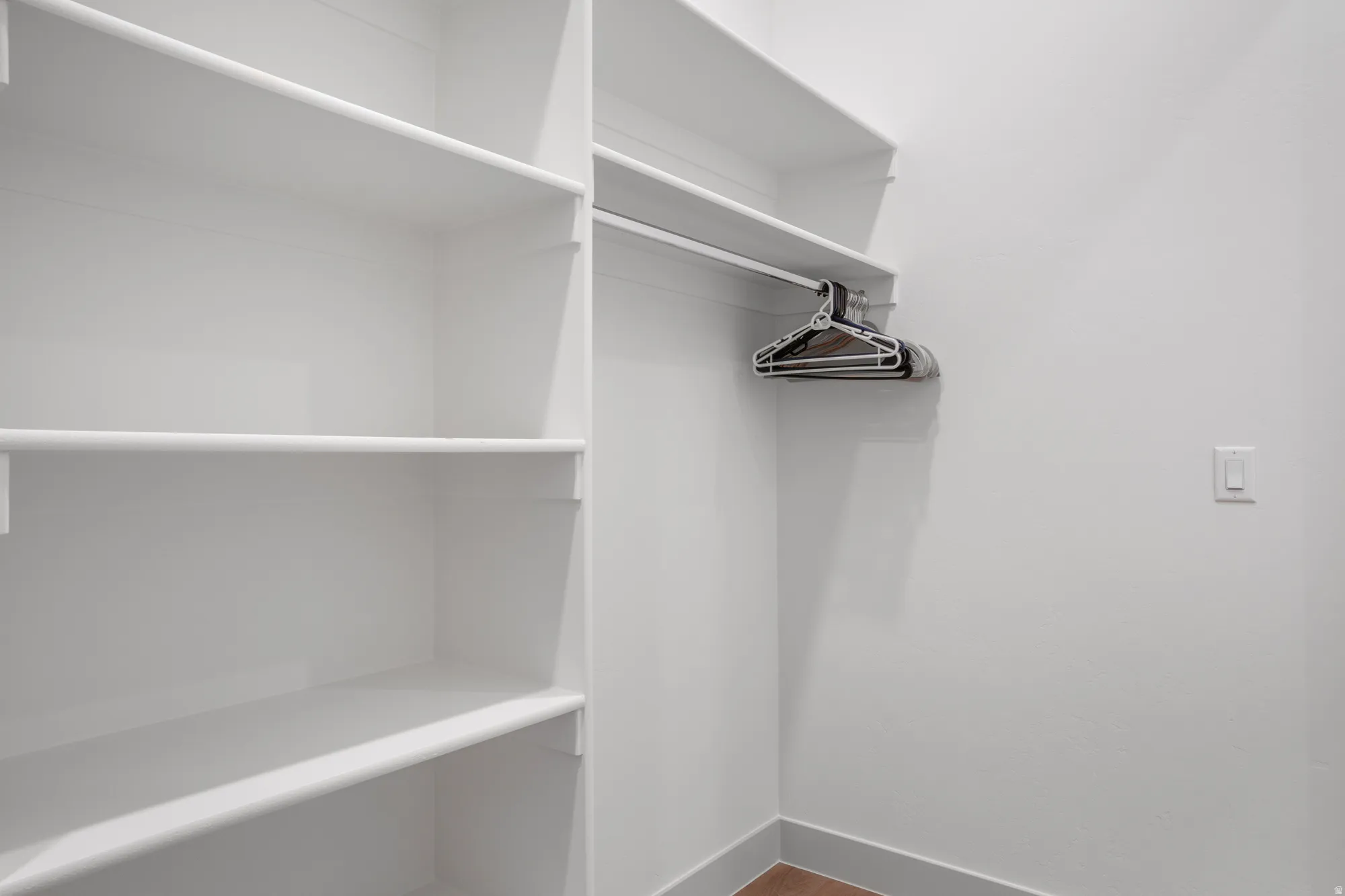 Walk in closet with dark wood-style flooring