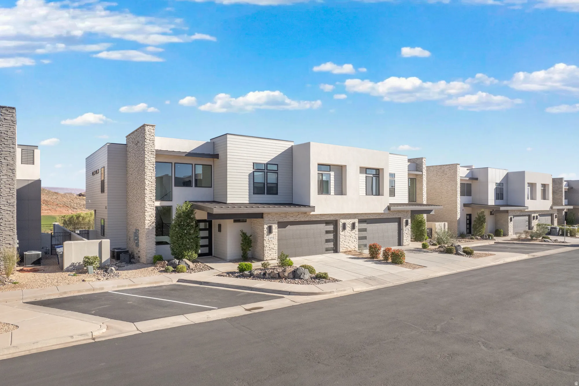 Contemporary home featuring stone siding, stucco siding, a residential view, and a garage