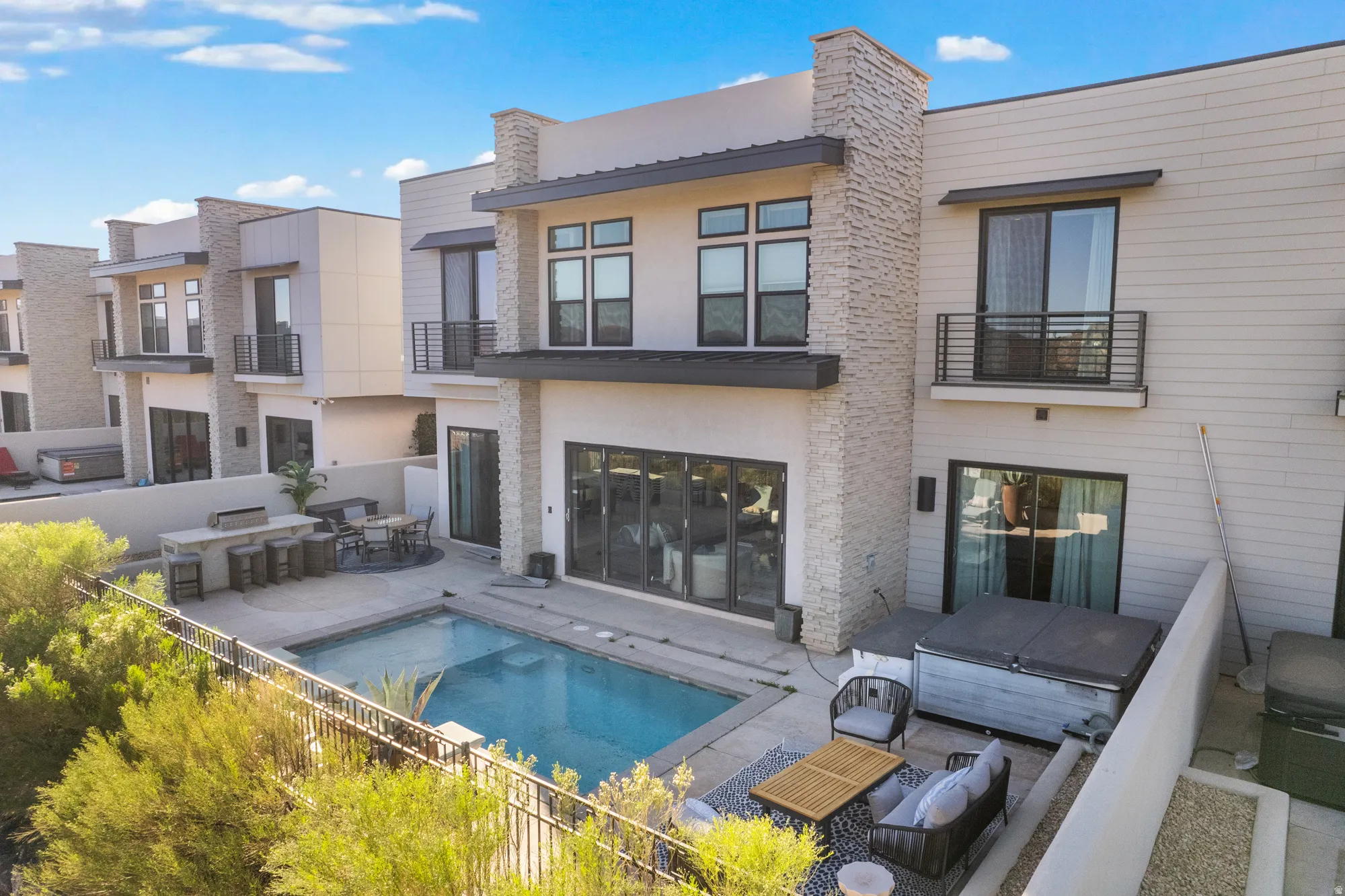 Rear view of property featuring stucco siding, a jacuzzi, a patio, and a balcony