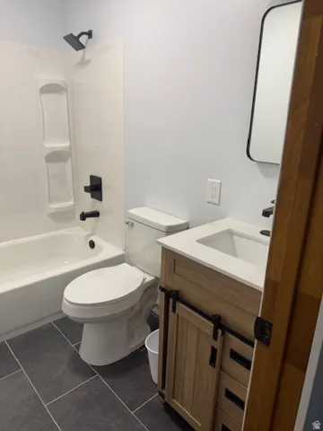 Full bathroom featuring vanity, shower / bathtub combination, and dark tile patterned floors