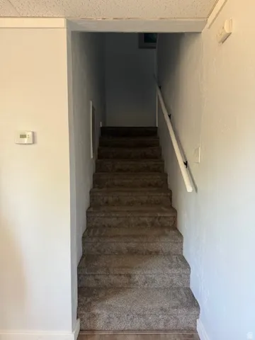 Stairs featuring wood finished floors and a textured wall