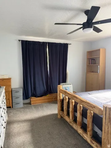 Carpeted bedroom featuring a textured ceiling and a ceiling fan