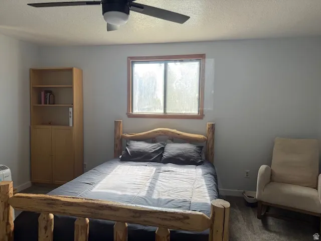 Bedroom featuring a textured ceiling, carpet flooring, and ceiling fan