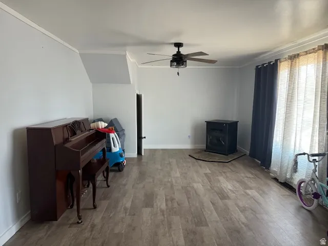 Sitting room featuring ornamental molding, a wood stove, light wood finished floors, and ceiling fan