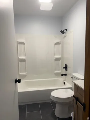 Full bathroom with vanity, dark tile patterned floors, and tub / shower combination