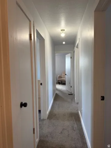 Corridor with a textured ceiling and light carpet