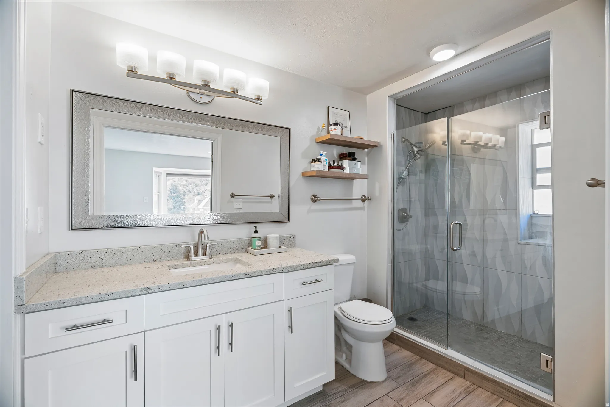 Bathroom featuring vanity, a shower stall, and wood finish floors