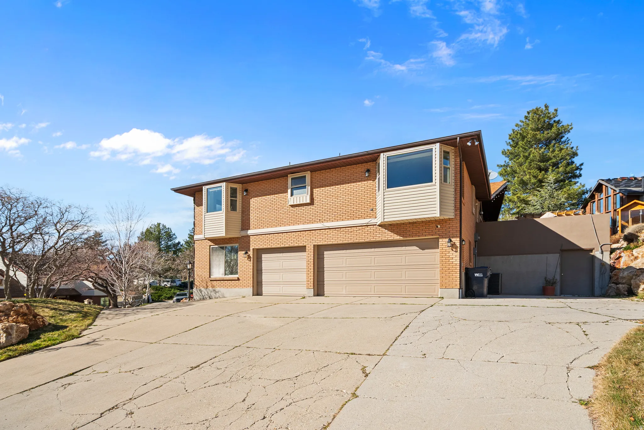 View of front facade with a garage, driveway, and brick siding