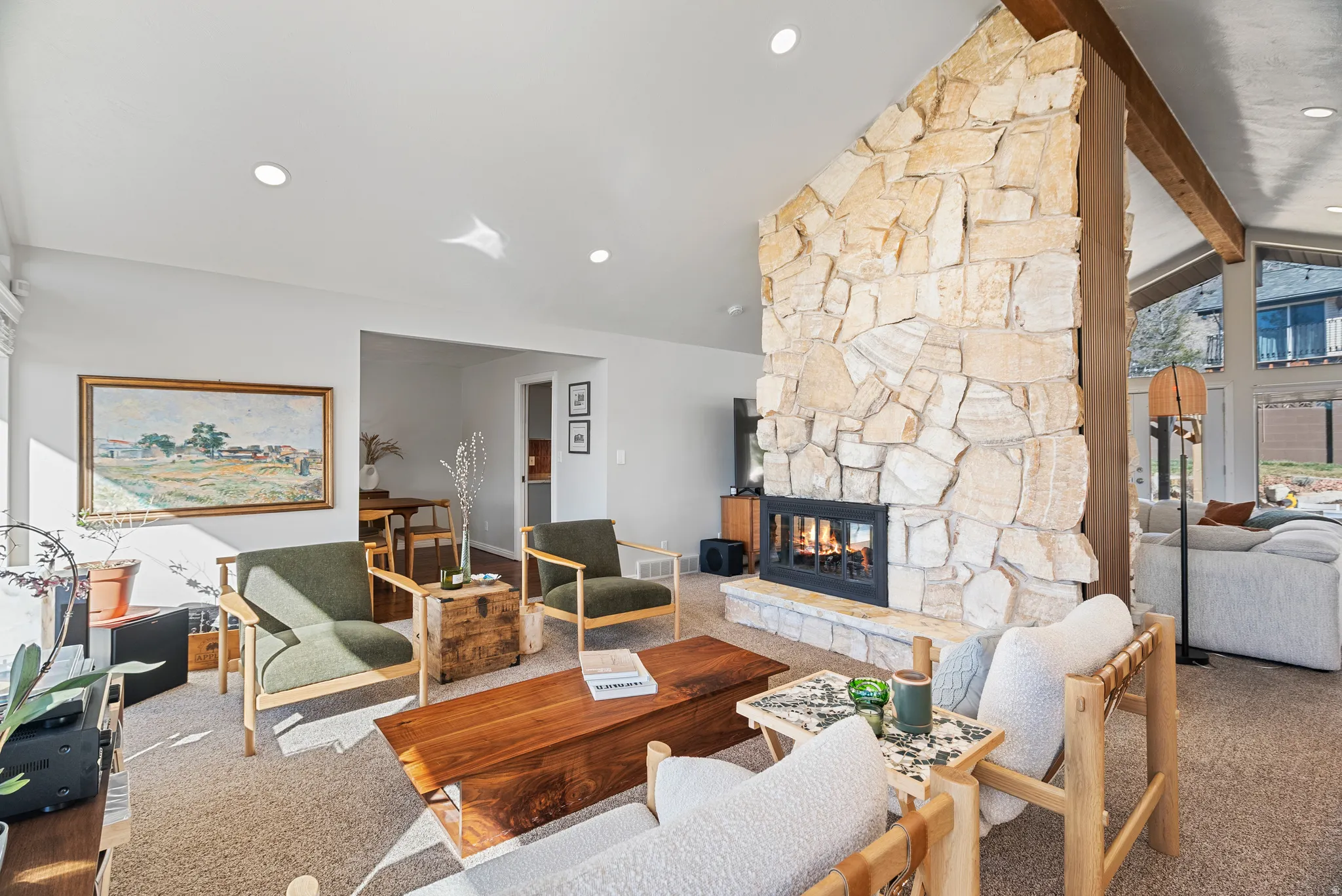 Living area featuring beamed ceiling, a stone fireplace, carpet, and recessed lighting