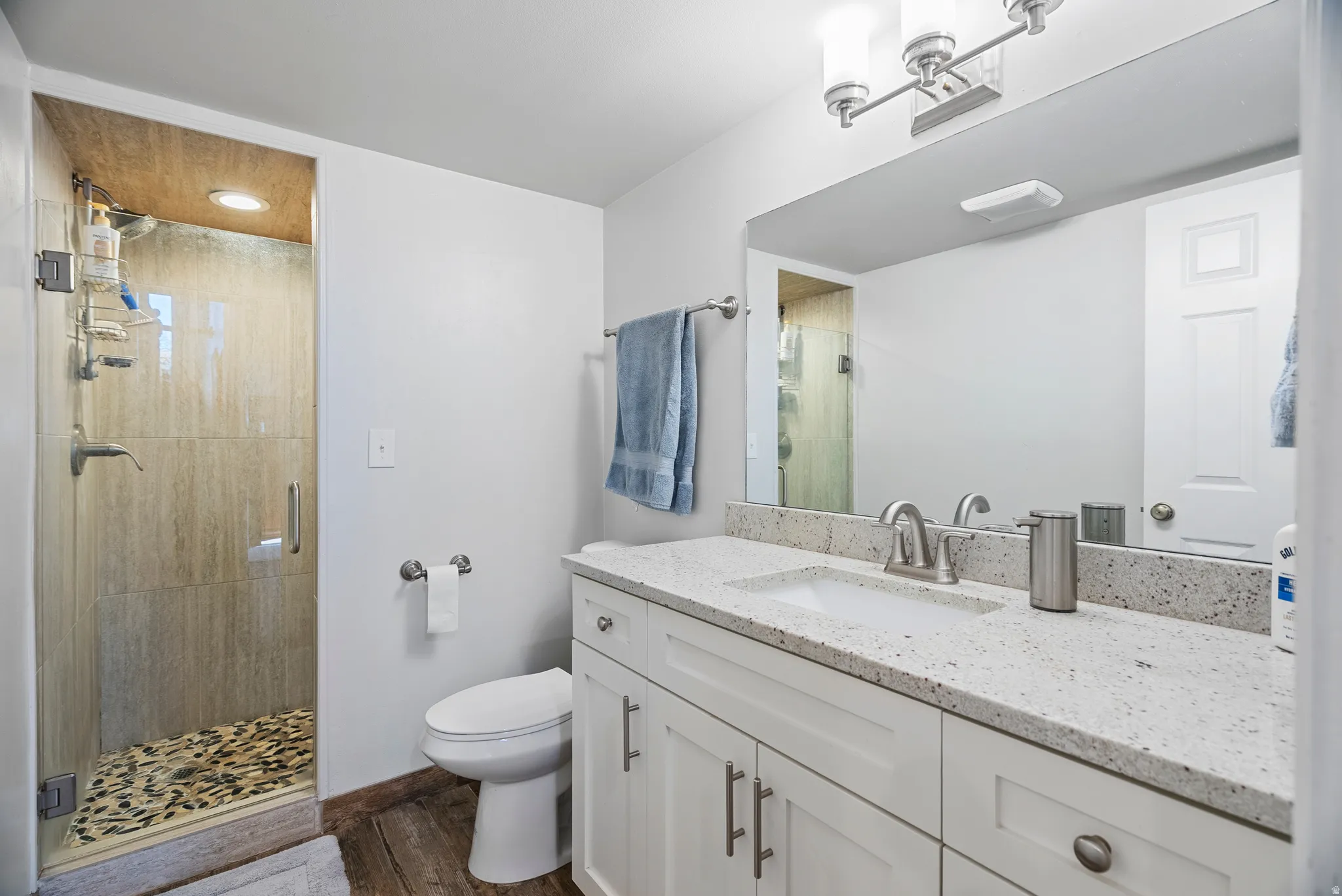Downstairs: Full bath with vanity, a shower stall, and dark wood-style floors
