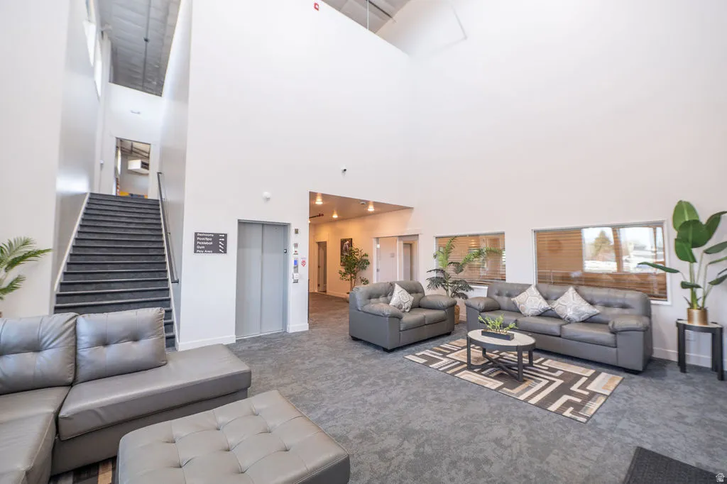 Carpeted living area featuring elevator and a high ceiling
