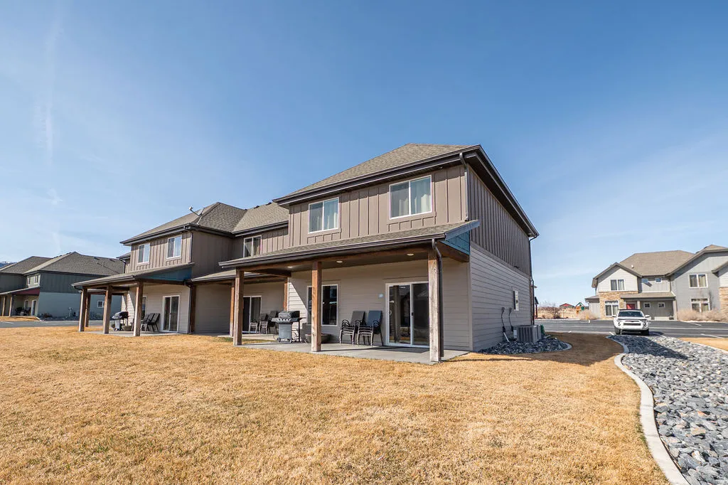 Back of house featuring a lawn, a patio, board and batten siding, and a residential view