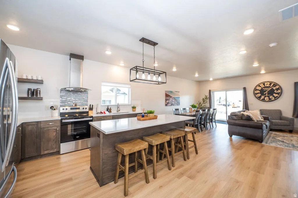 Kitchen featuring stainless steel appliances, a kitchen breakfast bar, dark wood finish cabinets, a kitchen island, and open floor plan