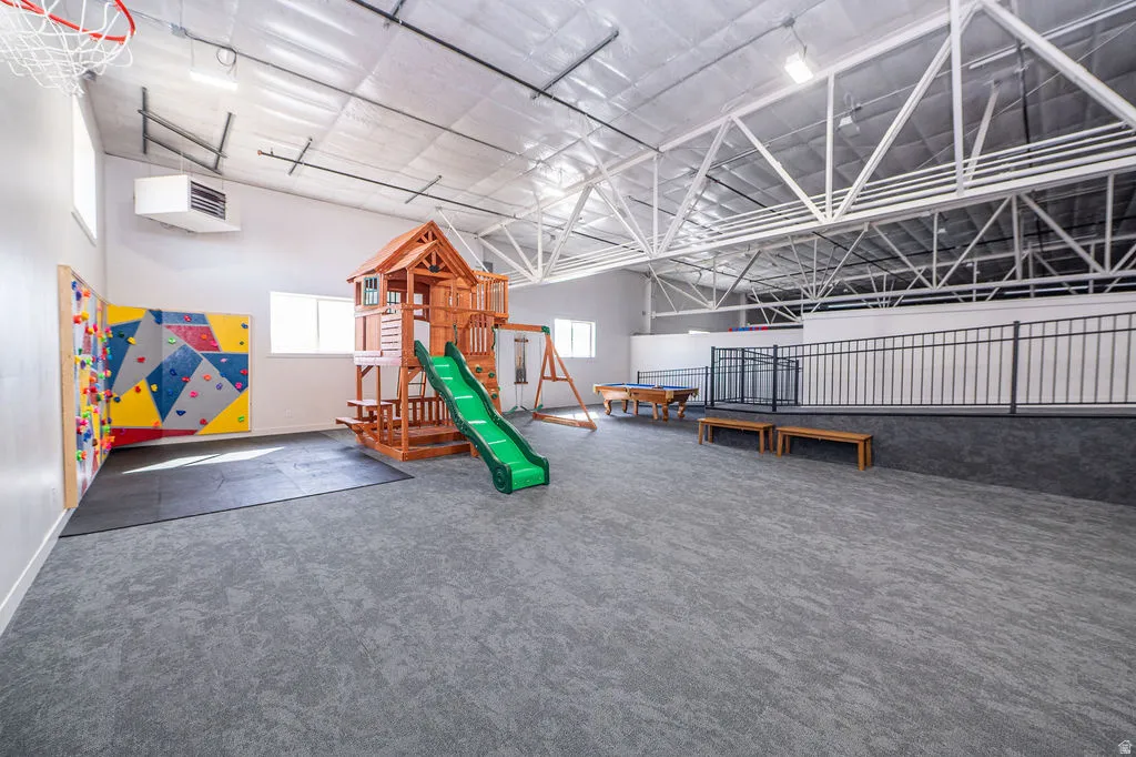 Recreation room featuring plenty of natural light, a heating unit, and a high ceiling