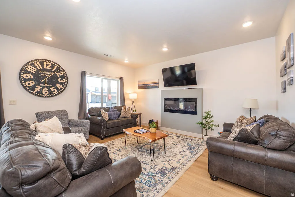 Living room featuring a glass covered fireplace, light wood finished floors, and recessed lighting