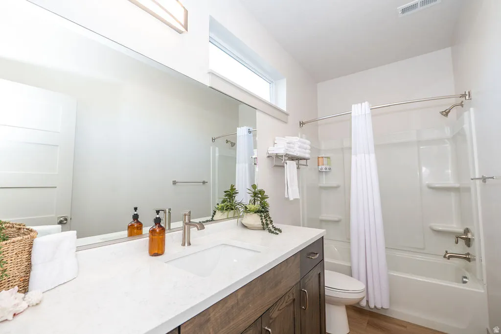 Full bathroom with vanity, shower / bath combo with shower curtain, and wood finished floors