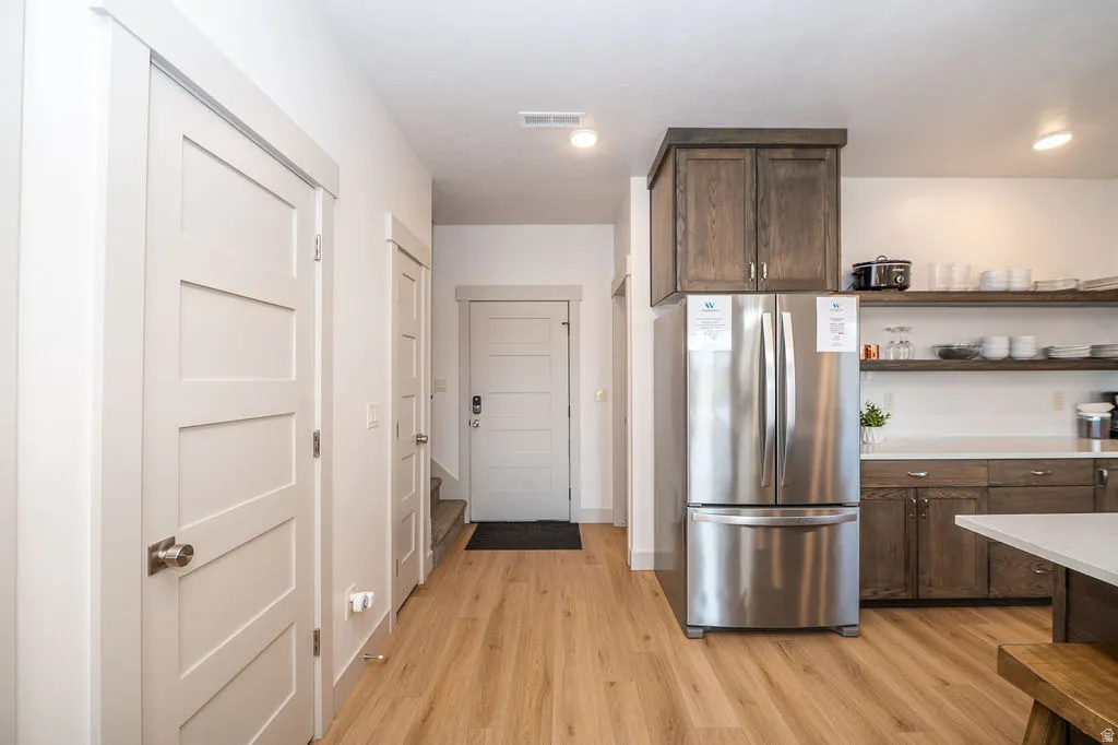 Kitchen with dark wood finish cabinetry, freestanding refrigerator, light wood-style floors, and open shelves