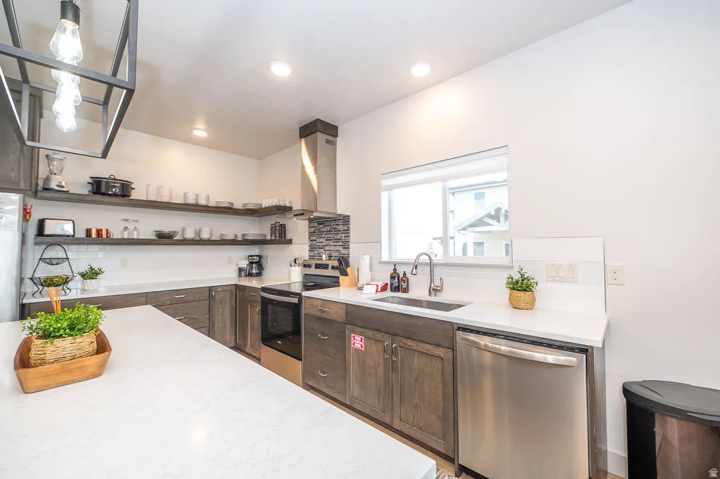 Kitchen with stainless steel appliances, ventilation hood, backsplash, light stone countertops, and recessed lighting
