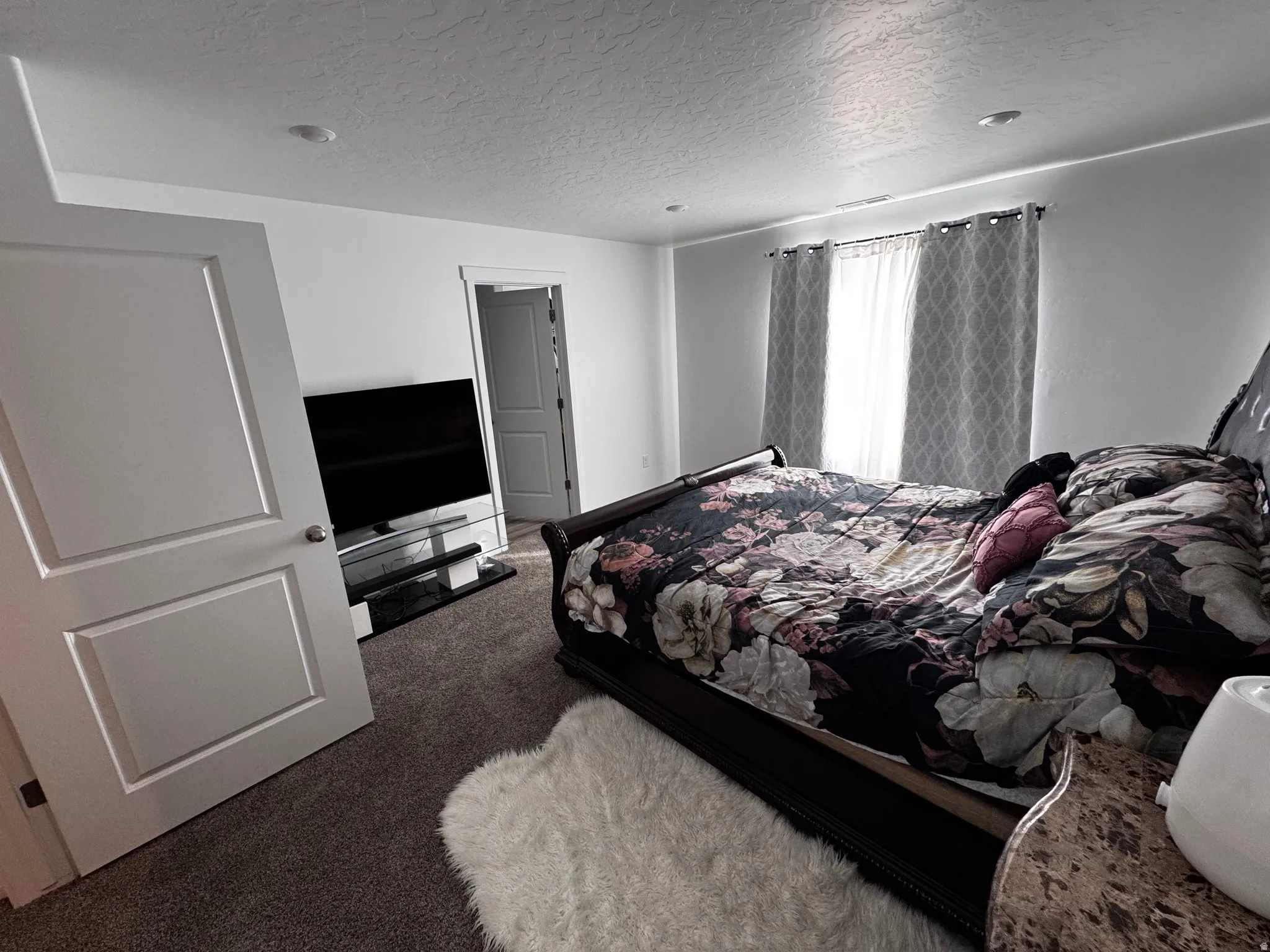 Bedroom with a textured ceiling and dark carpet