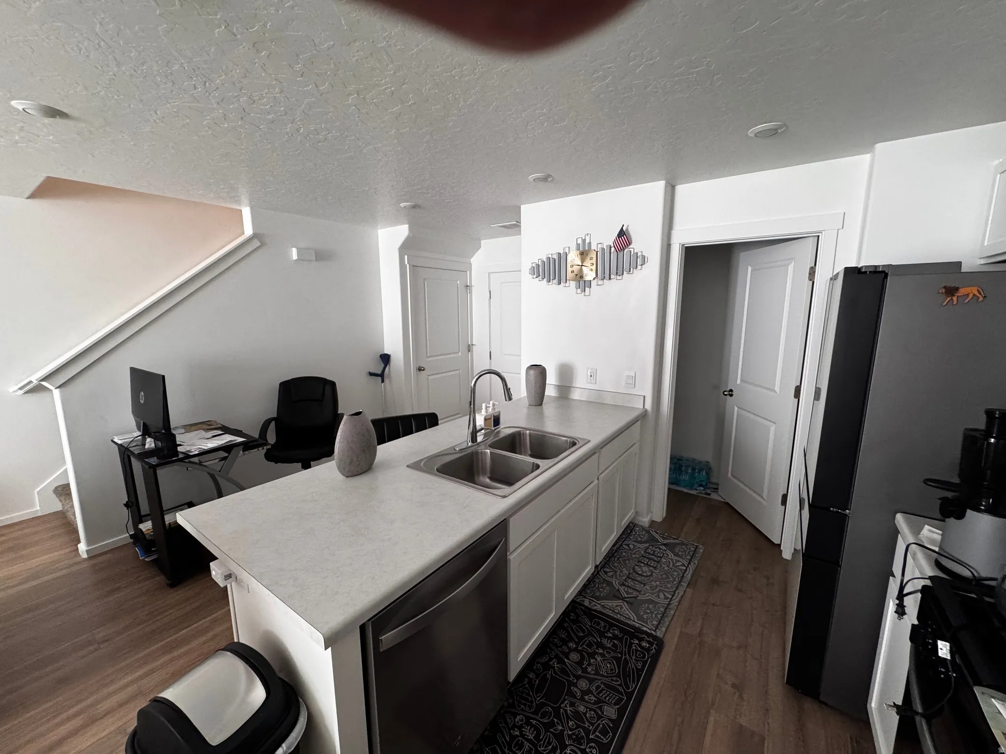 Kitchen featuring a peninsula, white cabinets, dark wood-style floors, stainless steel appliances, and a textured ceiling