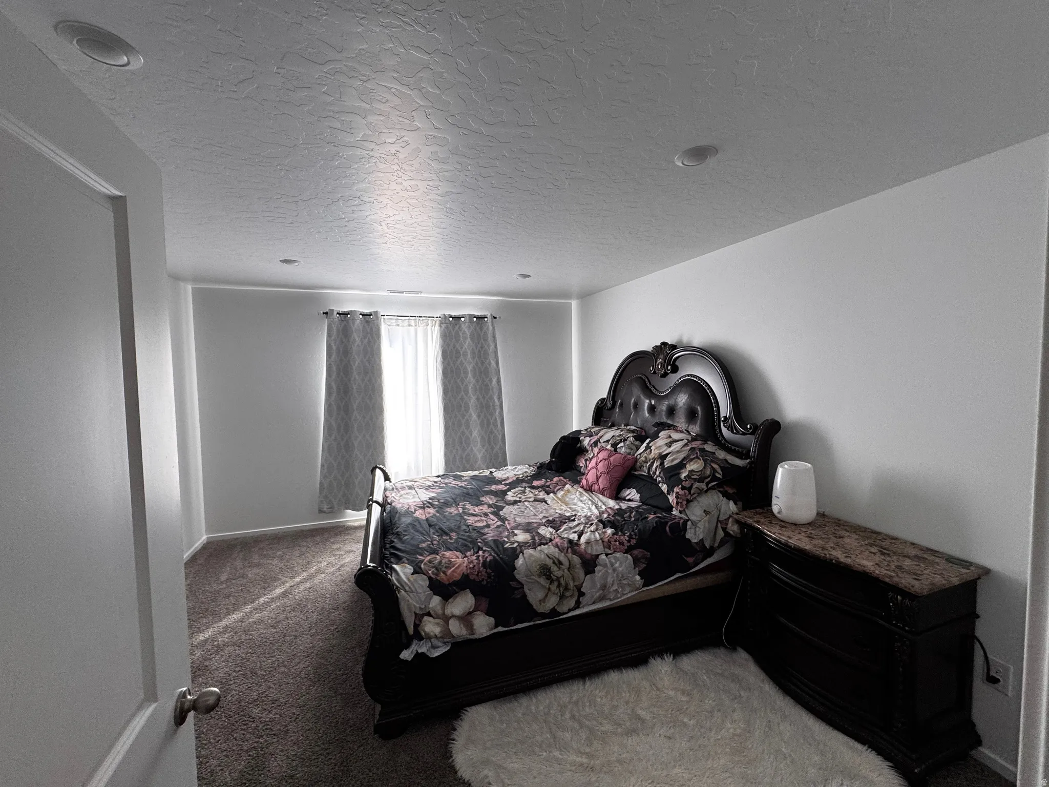 Carpeted bedroom featuring a textured ceiling and baseboards