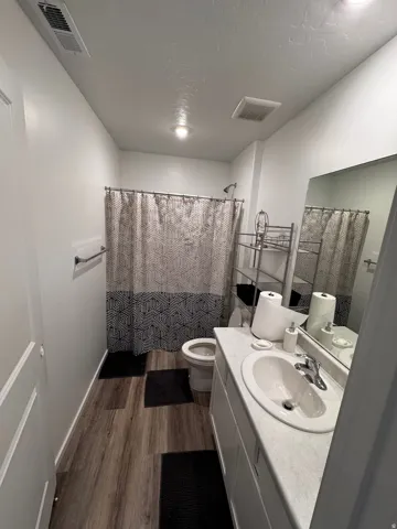 Bathroom with vanity, a shower with shower curtain, dark wood finished floors, and a textured ceiling