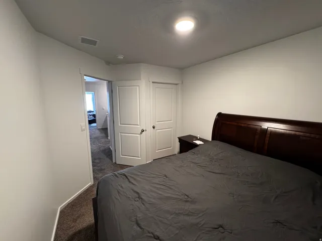 Bedroom with dark colored carpet and baseboards
