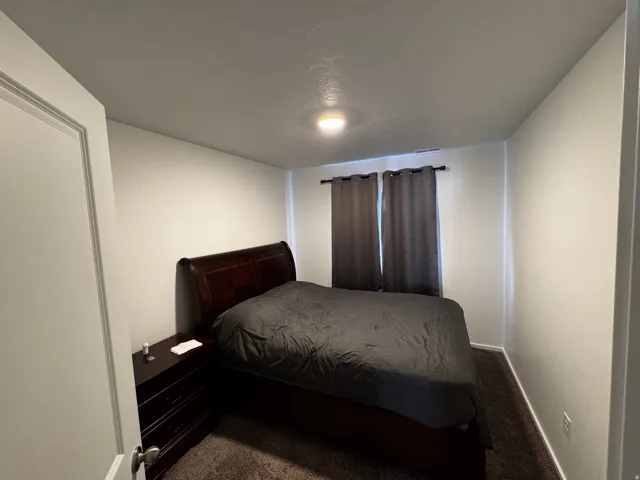 Bedroom featuring dark colored carpet and baseboards