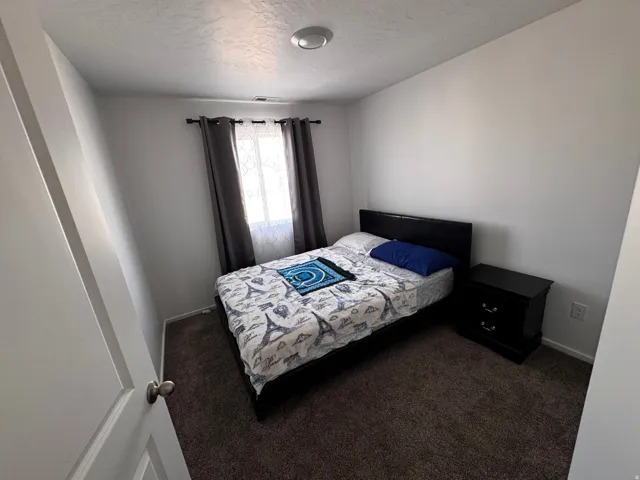Bedroom featuring dark carpet and a textured ceiling