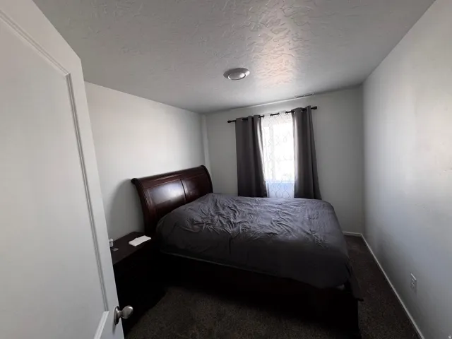 Bedroom featuring dark carpet and a textured ceiling