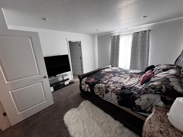 Bedroom with a textured ceiling and dark carpet