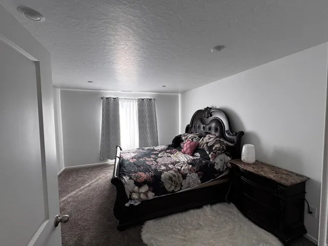 Carpeted bedroom featuring a textured ceiling and baseboards