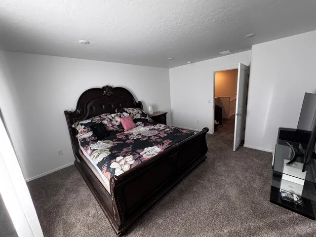 Bedroom featuring dark colored carpet and a textured ceiling
