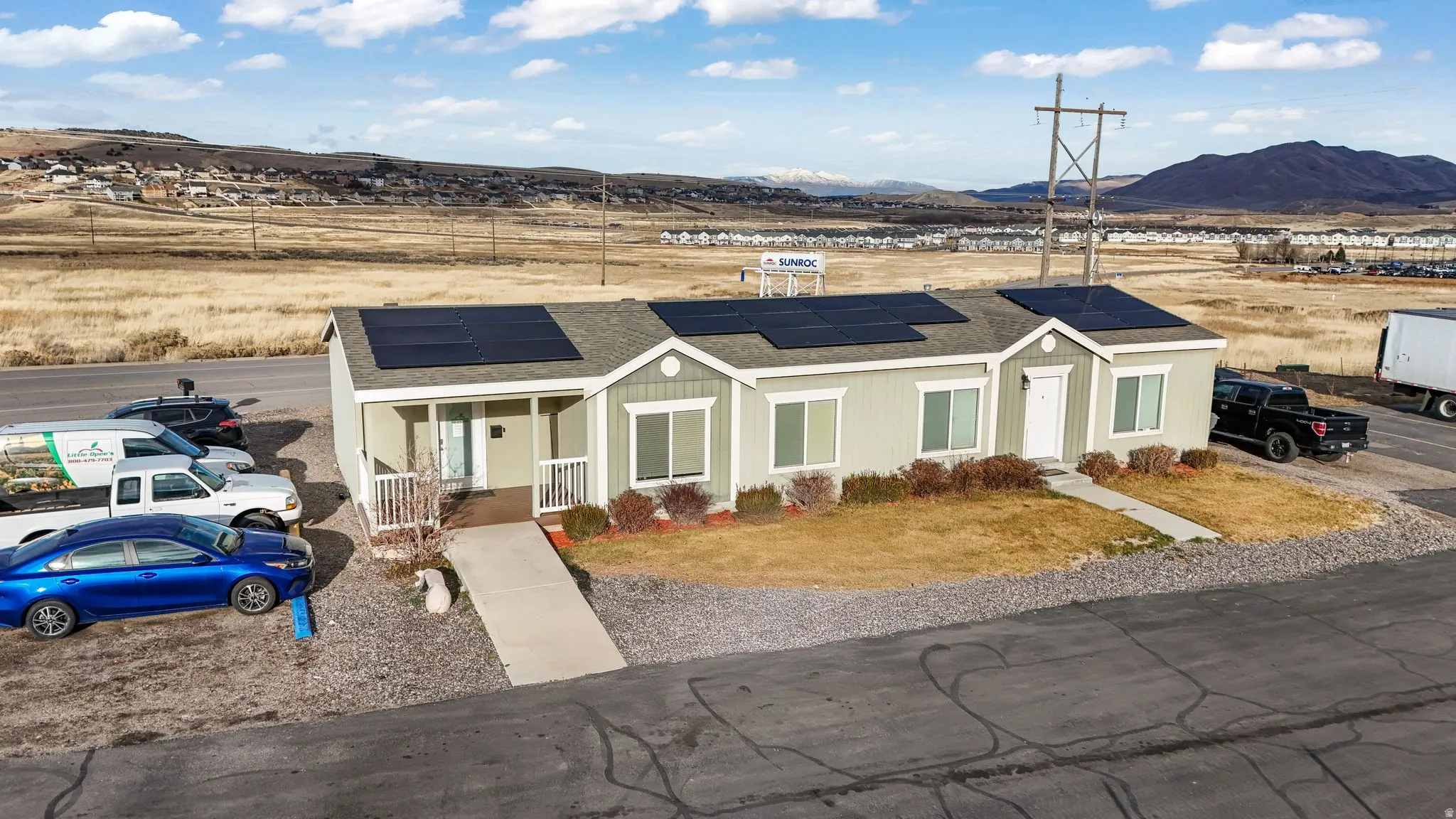 View of front of house featuring roof mounted solar panels, roof with shingles, a porch, a mountain view, and a front lawn