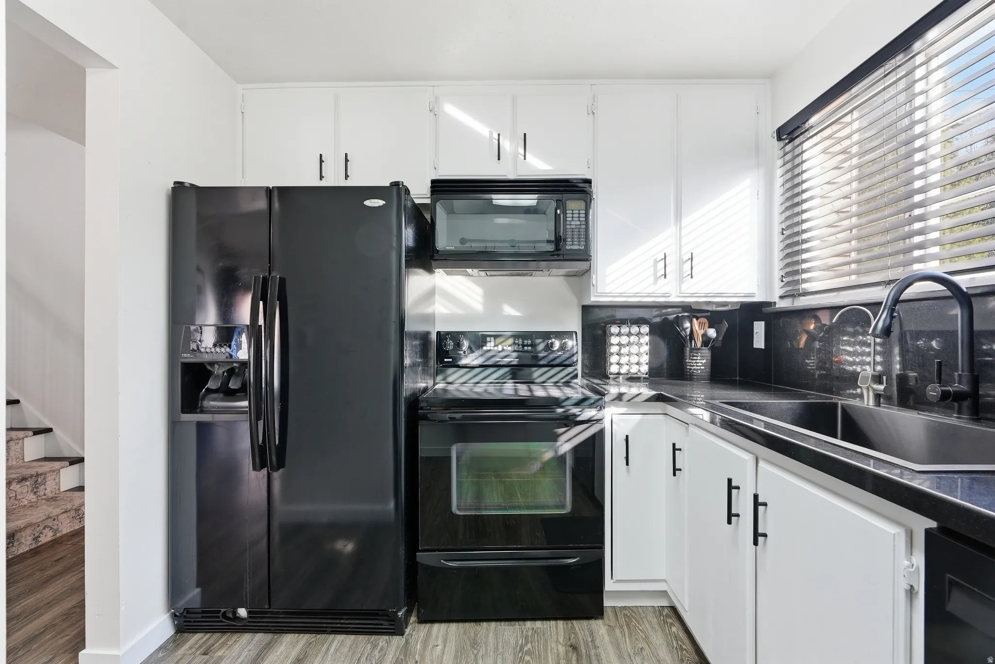 Kitchen with white cabinets, black appliances